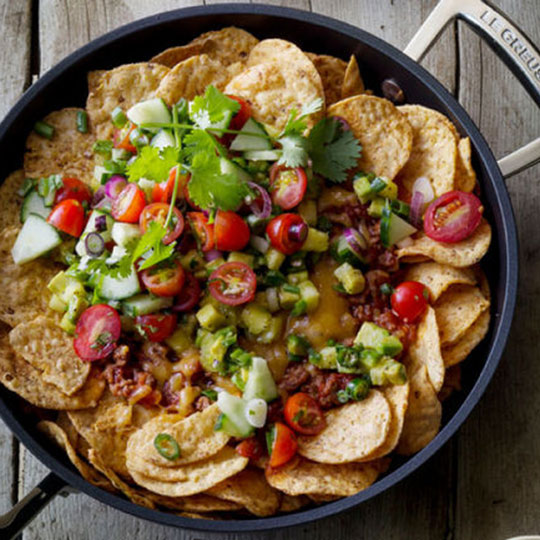 nachos in a nonstick briaser with  meat, cheese, lots of fresh veggies and jalapeños