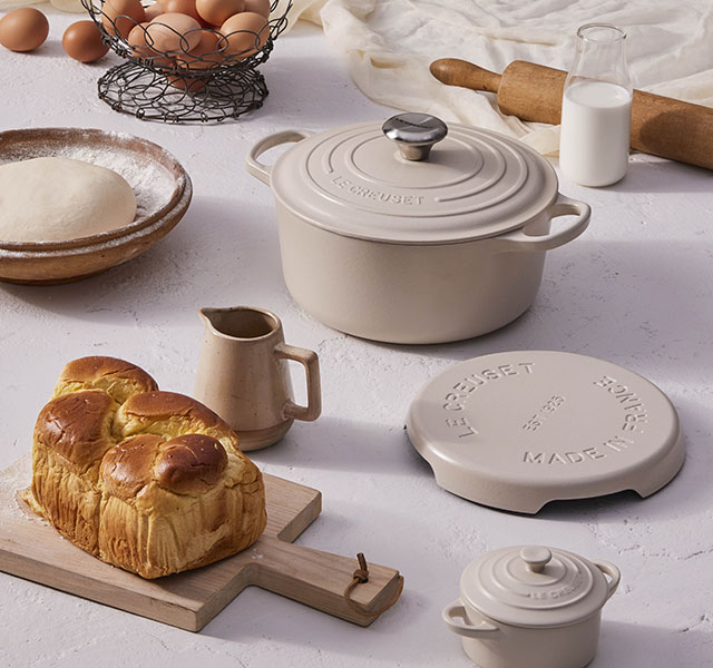 brown eggs, brioche bread and wooden tools arranged on a counter