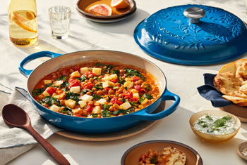 braiser with olive branch design embossed on the lid is filled with a chickpea stew
