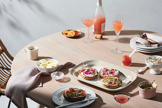 a table set for brunch with fruit and appetizers
