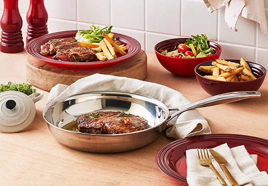 pork chops covered in sauce and chopped mango in a stainless steel fry pan