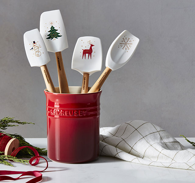 silicone tools in white with wooden handles and holiday images printed on the silicone - all inside a cerise red utensil crock