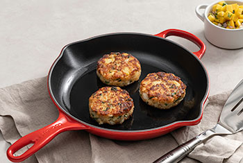fish cakes in a red enameled cast iron skillet