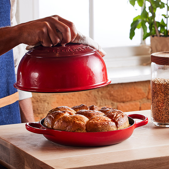 two loaves of freshly baked bread in front of a Le Creuset bread oven