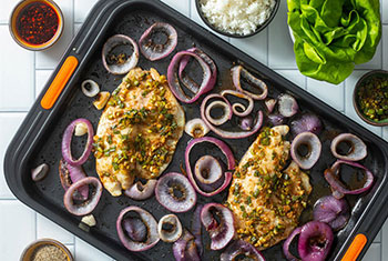 herbed chicken and red onions on a sheet pan