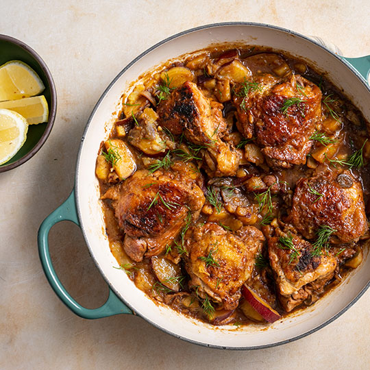 browned chicken thighs in a braiser with apples and vegetables