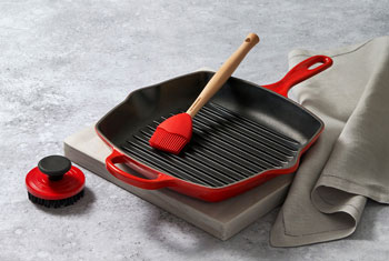 grill pan next to a grill brush and basting brush
