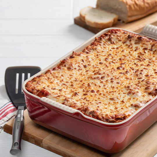 lasagna in a red stoneware baker