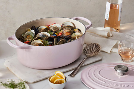 soft pink oval dutch oven filled with shellfish