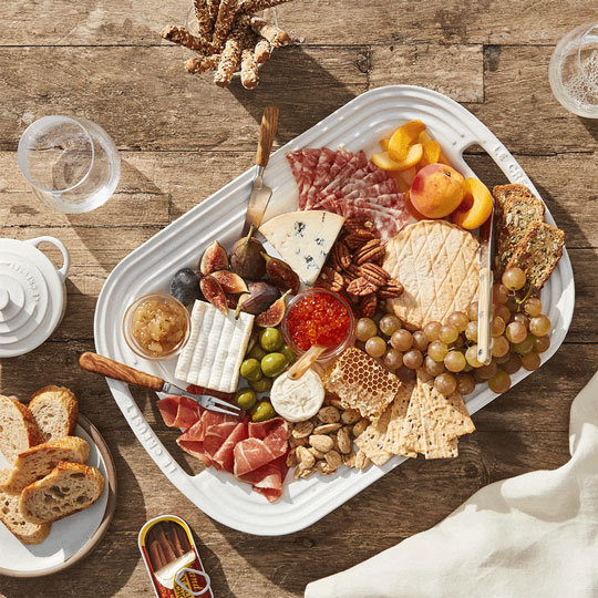 white platter overflowing with meat, cheese, fruit, nuts, spreads, honey and more