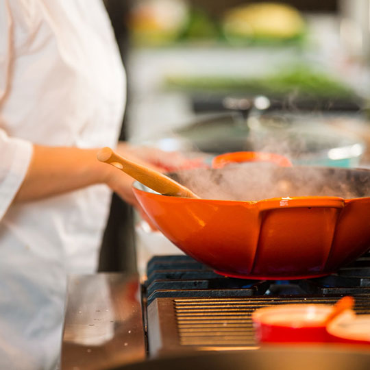 chef beside a steaming orange wok