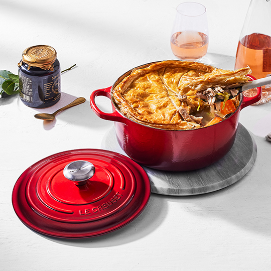Caribbean Blue Dutch Oven next to a towel and wooden spoon