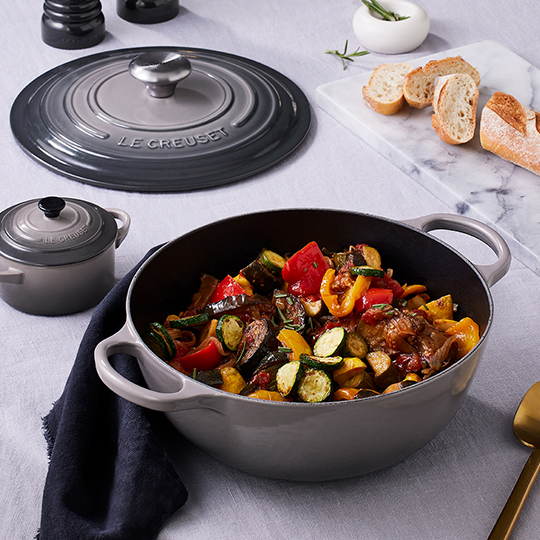 vegetables in a round shallow roasting pan with loop handles