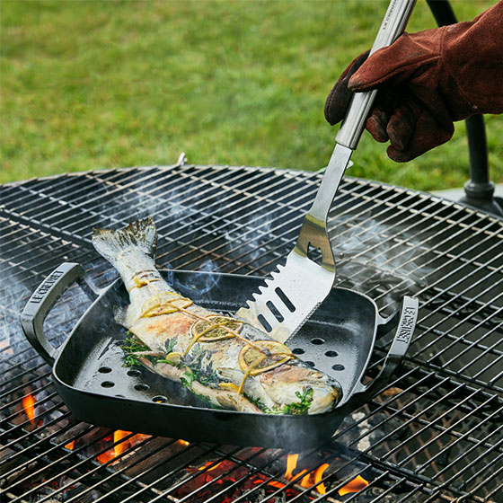 whole fish cooking in a grill basket on a grill