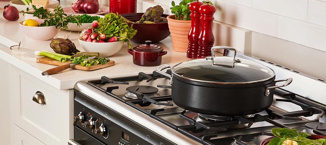 hands placing a cast iron braiser on a counter