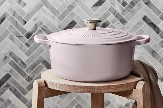 soft pink dutch oven against a gray tile backsplash