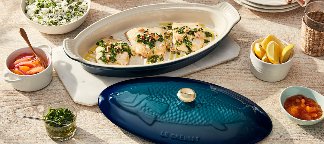 salmon in a stoneware baking dish with an embossed image of a fish on the lid