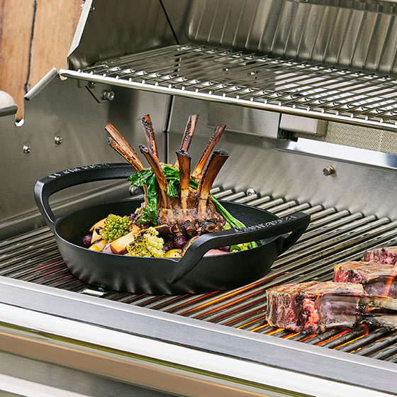 crown shaped rib roast in a skillet with two loop handles on a grill